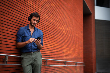 Young man listening to music. Urban fashion man with headphones enjoying the city.