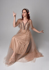 Full length  portrait of red haired  girl wearing a creamy fantasy gown and crystal crown, like a...
