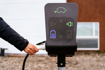 Unrecognizable person inserting charging electric car in station