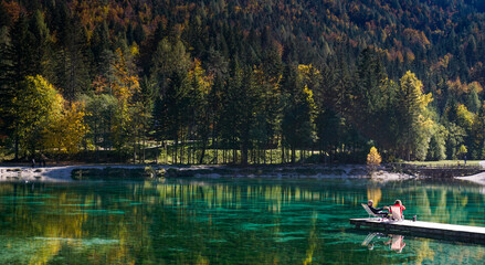 Fototapeta na wymiar tourists enjoy relaxing on the wooden dock at Lake Jasna in the Slovenian Alps