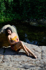 woman sunbathing in sarong on a rock near the river