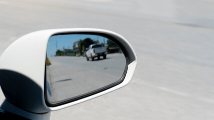 Traffic from behind through the mirrors wing of a white car. with blurred of other cars drving on the asphalt road at day.