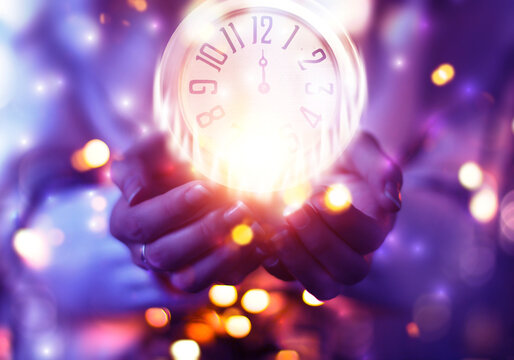 Women's hands are holding an antique clock. Midnight on an antique clock, blurred background. New Year's futuristic background, blurred light lines, bokeh, snowflakes