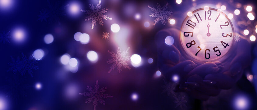 Women's hands are holding an antique clock. Midnight on an antique clock, blurred background. New Year's futuristic background, blurred light lines, bokeh, snowflakes - Powered by Adobe