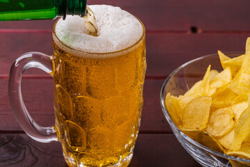 Close up view of beer pouring into glass mug and cup of potato chips. Sweden.