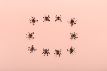 minimalistic frame for halloween celebration on light pink background. decor for halloween in the form of black spiders. concept for holiday postcard, banner with place for text. simple top view