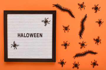 halloween, decoration and scary concept. halloween lettering decorated with spiders. scary halloween pattern of various insects in black on a bright orange background backdrop