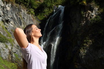 Naklejka premium Relaxed woman breathing fresh air and resting in a waterfall