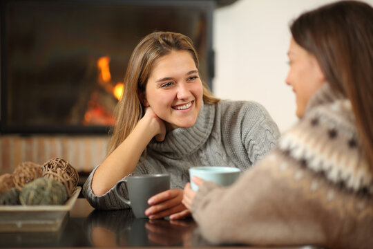 Happy women talking beside a fireplace at home