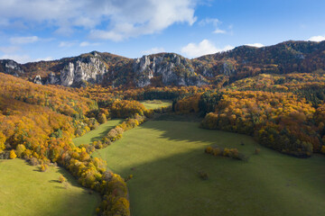 Scenic landscape in Sulov, Slovakia, on beautiful autumn sunrise with colorful leaves on trees in forest and bizarre pointy rocks on mountains and slight mist in the valleys and dramatic clouds on sky