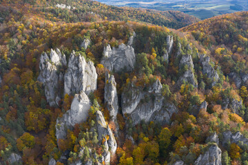 Scenic landscape in Sulov, Slovakia, on beautiful autumn sunrise with colorful leaves on trees in forest and bizarre pointy rocks on mountains and slight mist in the valleys and dramatic clouds on sky