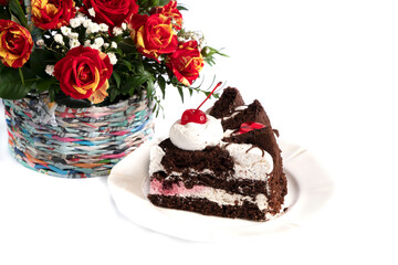 
festive cake. a piece of cake decorated with cherries stands near a bouquet of roses.