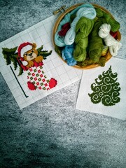Christmas cross-stitch embroidery and woolen threads on the gray background 