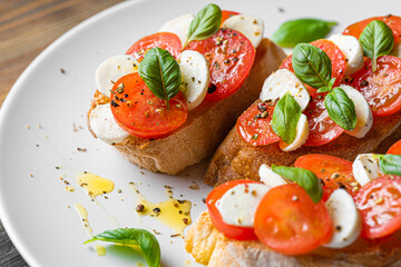 bruschetta caprese. fresh basil leaves, ripe aromatic tomatoes and Italian mozzarella on bruschetta, drizzled with olive oil and sprinkled with pepper and herbs.