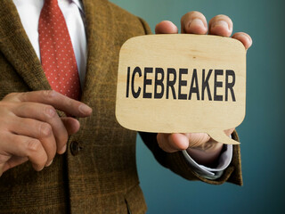 Man in suit shows Icebreaker sign on the plate. - obrazy, fototapety, plakaty