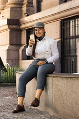 Fototapeta na wymiar Overweight vintage woman with beret making an on-line purchase with smart phone outdoors in of old building. E-commerce, online shopping, communication concept.