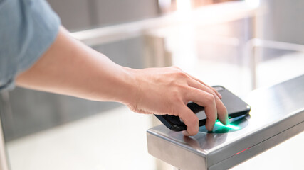 Fototapeta premium Male hand using smartphone to open automatic gate machine in office building
