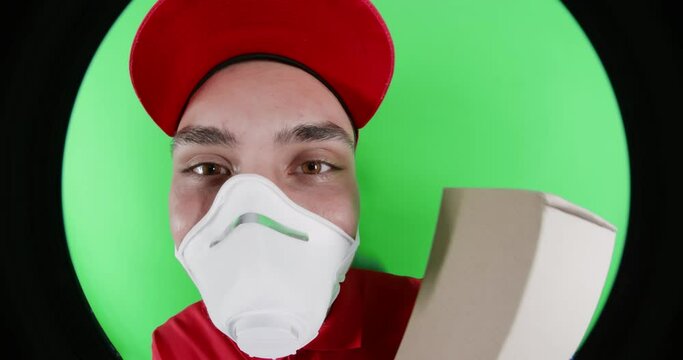 Courier in protective mask looking into door spyhole
