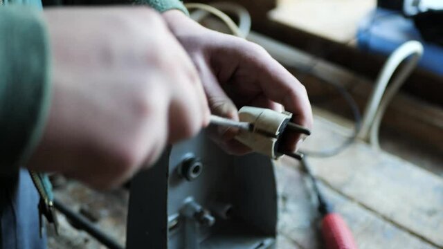 Electrician disassemble an old electrical plug in a small workshop