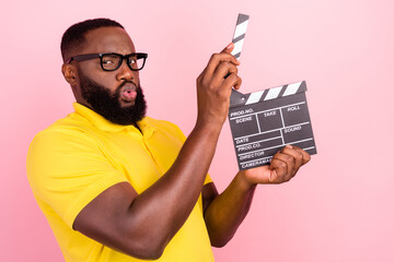 Photo of afro american brown haired man wear glasses yellow t-shirt hold clapper glasses isolated on pink color background