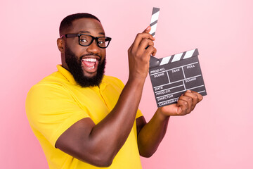 Photo of happy trendy afro american cheerful brown haired man hold hands clapper isolated on pink...