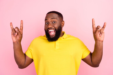 Portrait of attractive cheerful guy showing double horn sign isolated over pink pastel color background