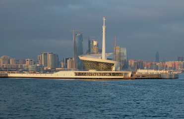Lighthouse in the Baku Bay against the background of high-rise buildings under construction, morning haze. Azerbaijan