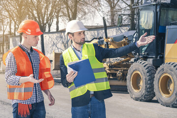 Two construction engineers inspect the construction site and discuss the implementation of the plans.