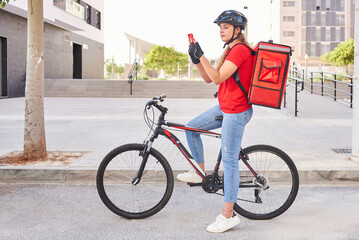 A cyclist delivery girl checks the address of her next shipment with her mobile phone