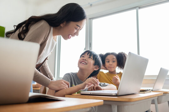 Happy Smiling Asian female teacher is teaching and advice her Asian boy learning on laptop.