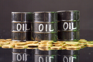 Barrels with oil and golden coins on the reflective desk.