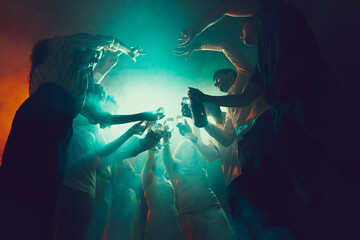 Group of young, active people at the night club, party dancing in neon lights, drinking cocktails - obrazy, fototapety, plakaty