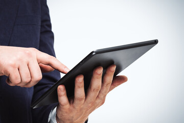 Businessman holds digital tablet and clicks on screen, close up. Search concept