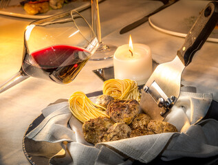 Alba white truffles in napkin with raw egg tagliolini and steel truffle cutter on the restaurant table with burning candle and goblet of red wine, nebbiolo or barbera wine - obrazy, fototapety, plakaty