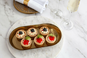 canape with black caviar and soured cream near glass with champagne