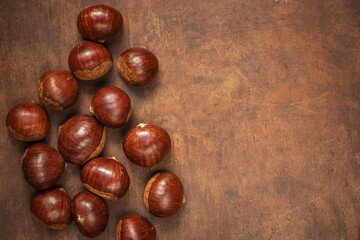 Chestnuts on on an old board with copy space. Autumn fall concept. Horse chestnuts top view.