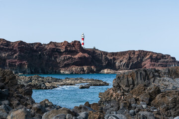 Fototapeta na wymiar Rocky coast of the Atlantic Ocean at Cape Teno. A lighthouse in the background. Tenerife. Canary Islands. Spain.