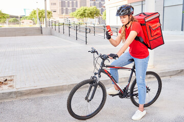 A cyclist delivery girl checks the address of her next shipment with her mobile phone