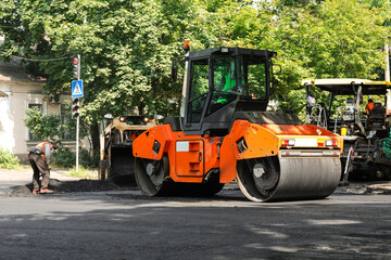 MYKOLAIV, UKRAINE - AUGUST 05, 2021: Workers laying new asphalt with heavy machinery on city street. Road repair service