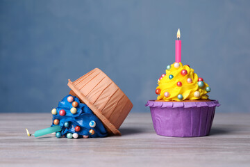 Dropped and good cupcakes on white wooden table. Troubles happen