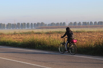 Giovane donna che pedala su una strada di campagna