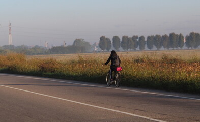 Giovane donna che pedala su una strada di campagna
