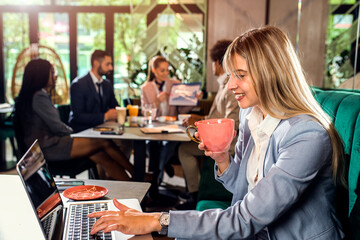 Young business woman working at cafe using laptop.