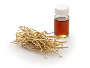dried vetiver roots and vetiver essential oil in a glass vial, fragrance material