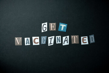 Get vaccinated words. Caption, heading made of letters with different fonts on a dark background.