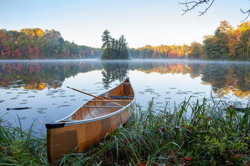 Yellow canoe on shore of beautiful lake with island in northern Minnesota at dawn - Powered by Adobe