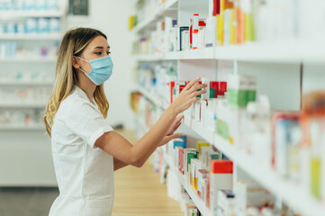 Pharmacist wearing protective mask and choosing medicine in pharmacy store