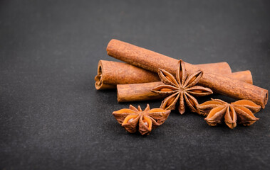 Aromatic spices cinnamon sticks and star anise on black background