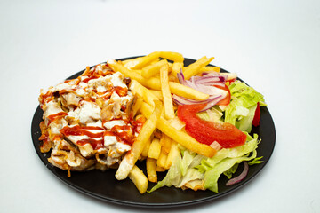 Donner kebab with chips and salad,  on a black plate isolated on white background.