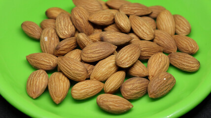 The pile of almonds is on a green plate